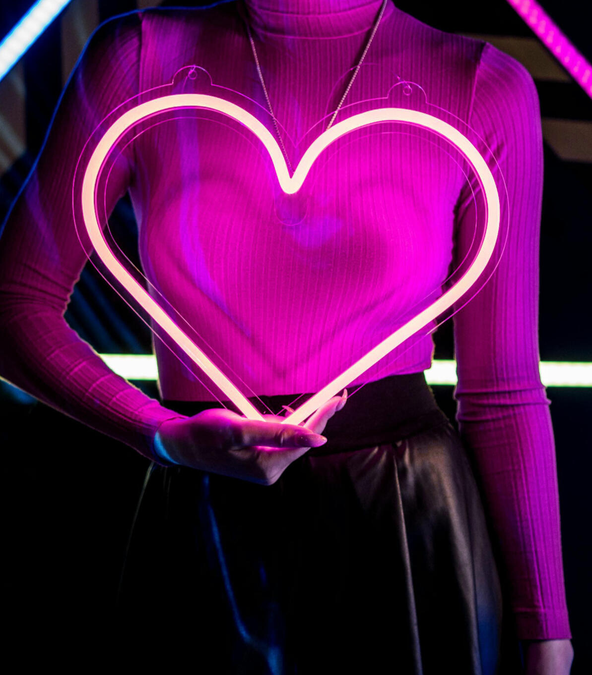 Woman holding a neon heart.